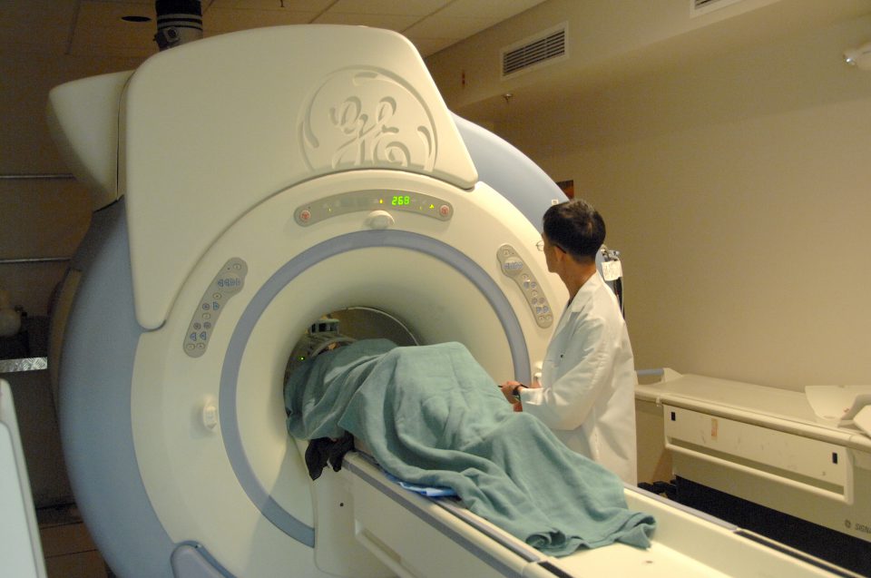 Magnetresonanztomografiegerät mit Techniker und Patientin.