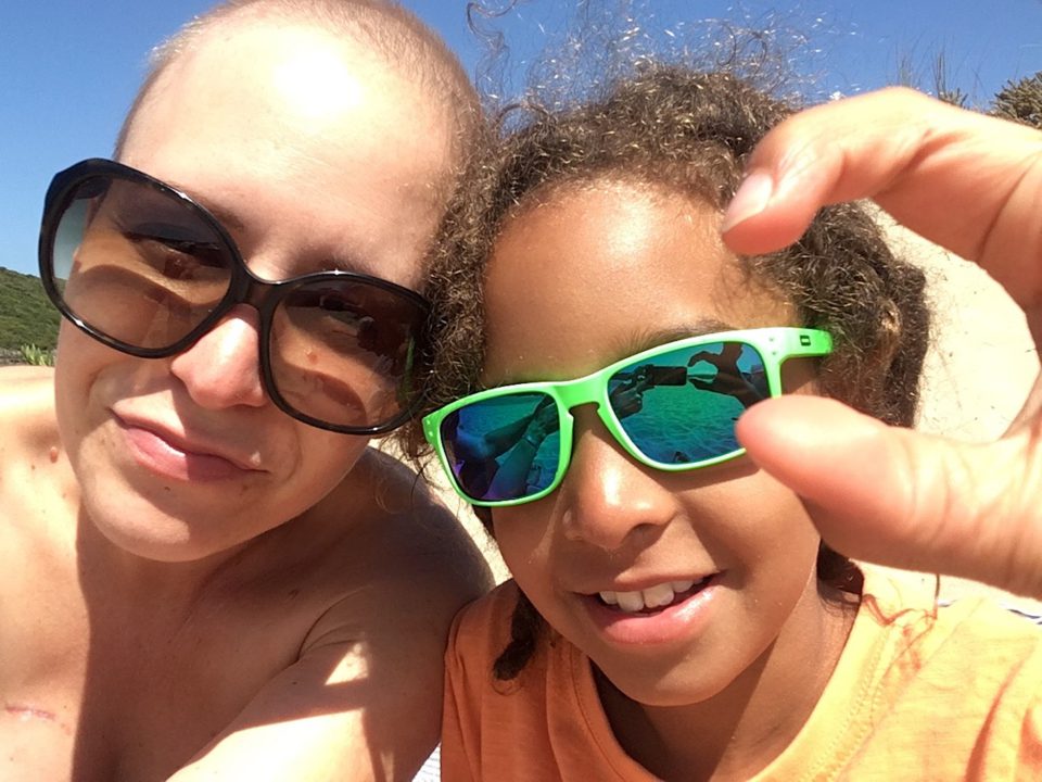 Frau mit Kind, beide tragen Sonnenbrillen.
