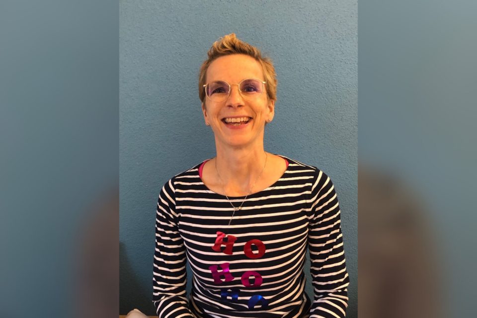 Lachende Frau mit frechem Kurzhaarschnitt in einem gestreiften Shirt mit der Aufschrift „Ho, Ho, Ho“.