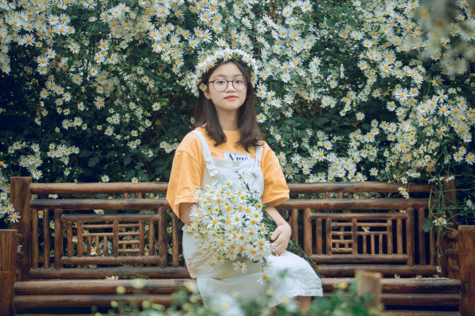 Ost-Asiatische Frau mit einem Strauß Gänseblümchen in der Hand
