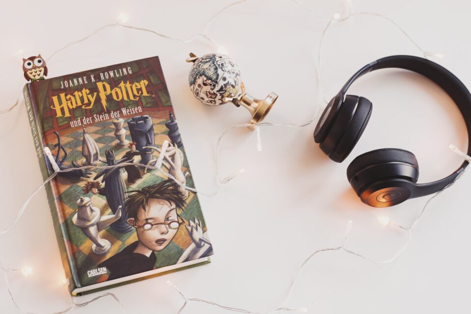 Harry Potter Buch, Kopfhörer und ein Globus liegen auf einer Tischplatte