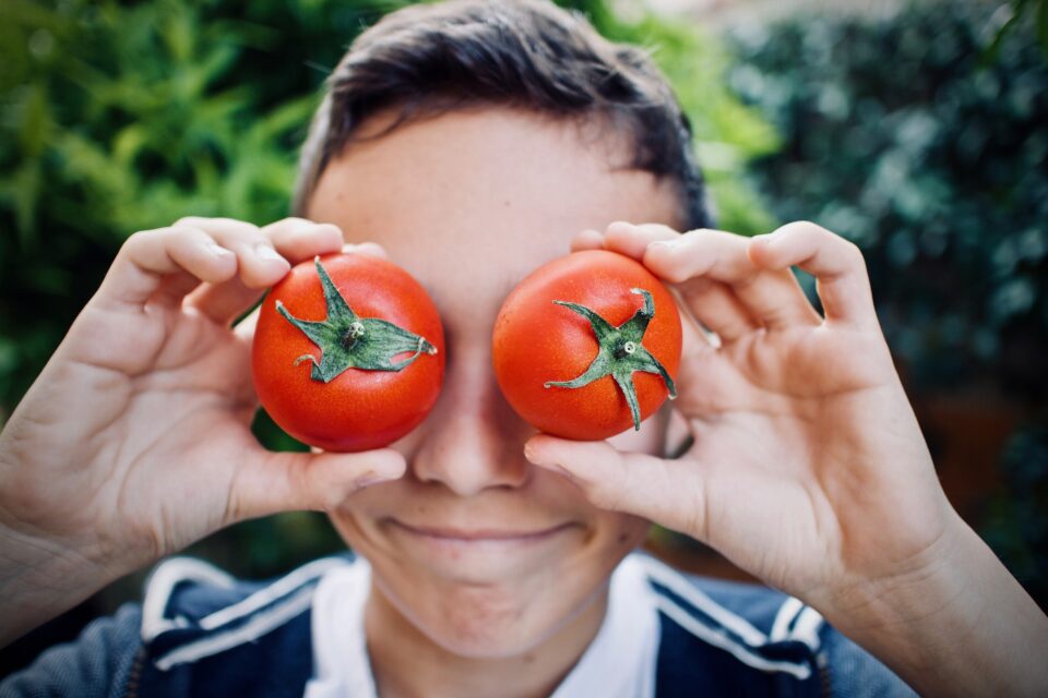 Junge, der sich zwei Tomaten vor die Augen hält