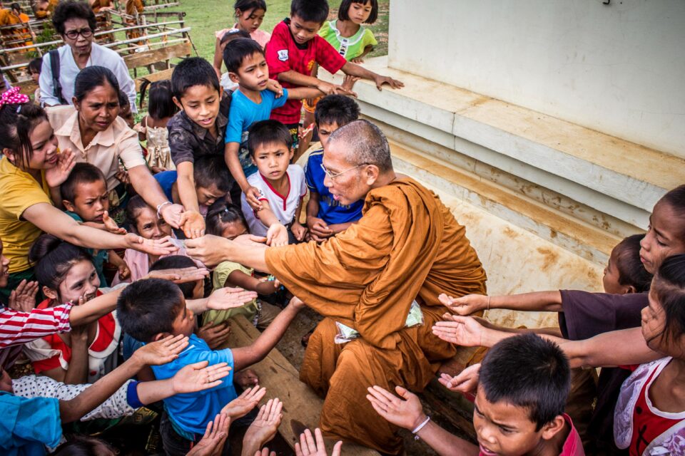 buddhistischer Mönch gibt vielen Kindern die Hände