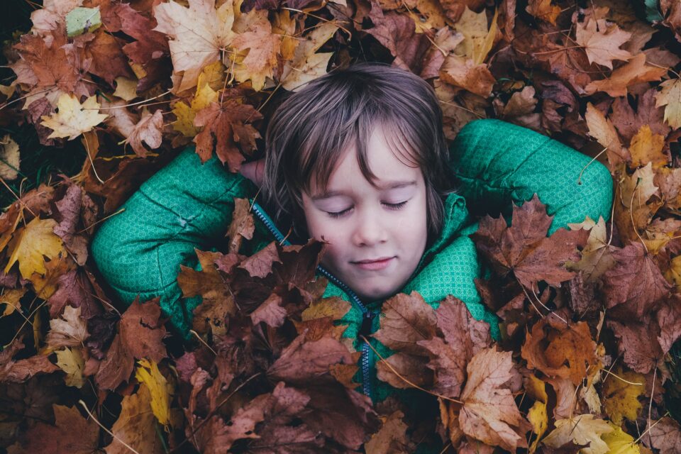 Kind schläft im Herbstlaub