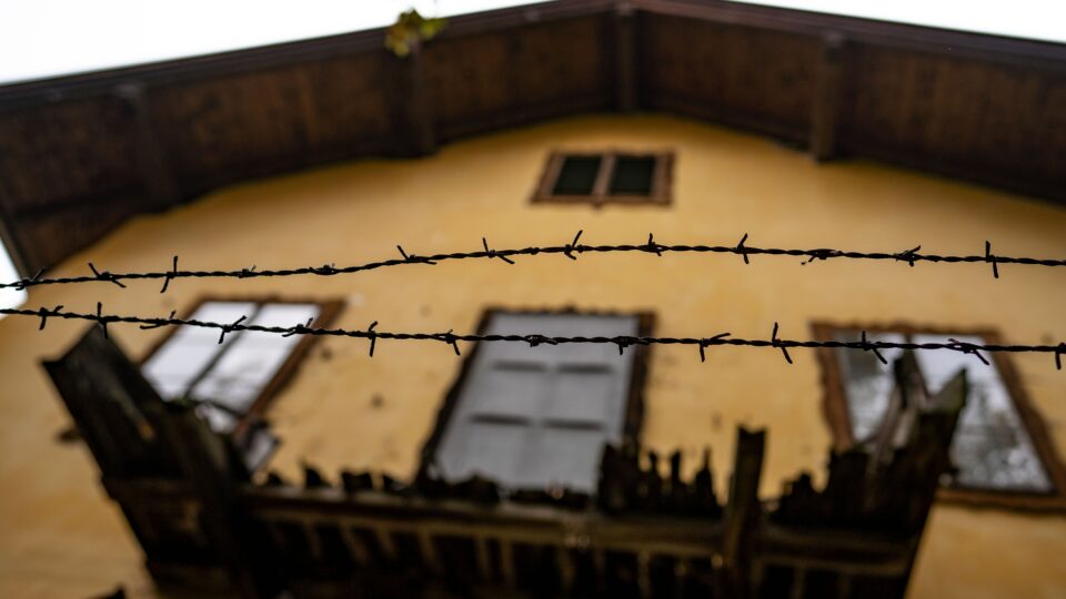 Hausgefängnis gelbes Haus umgeben von einem Stacheldrahtzaun