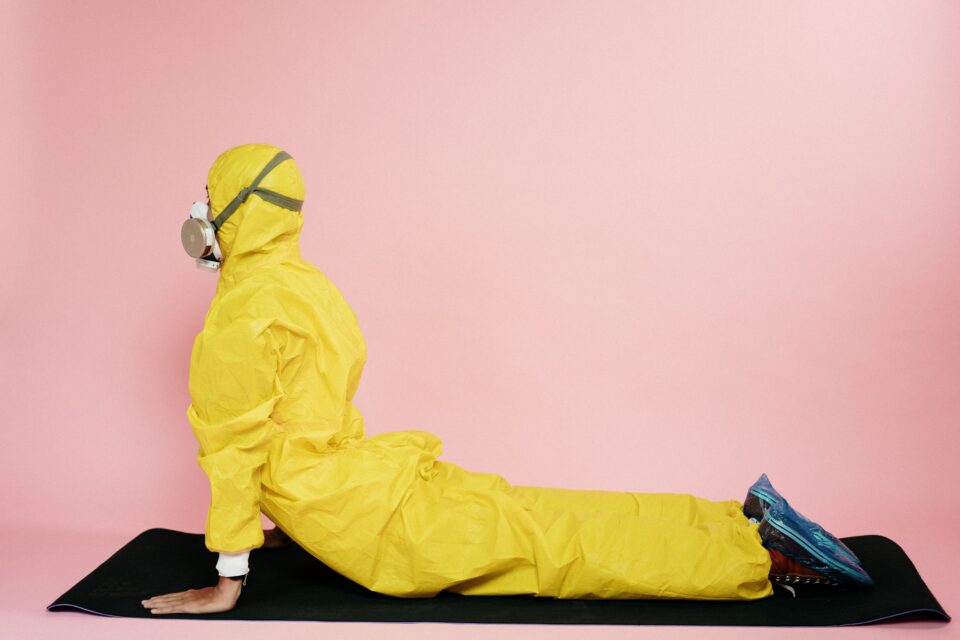 Person in gelbem Ganzkörperanzug macht Yoga.