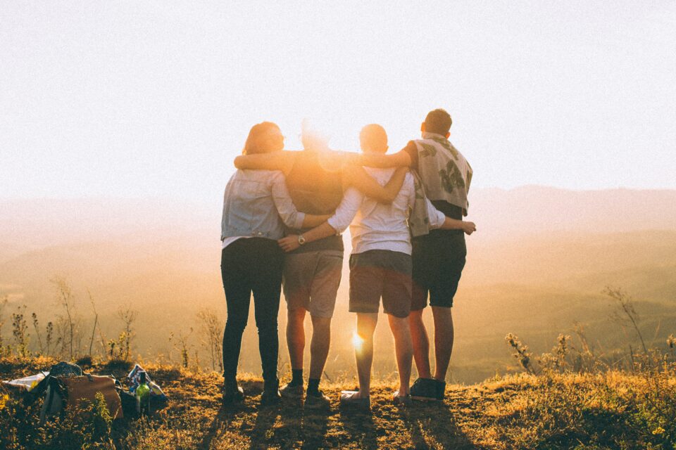 Vier Freunde stehen Arm in Arm im Sonnenuntergang