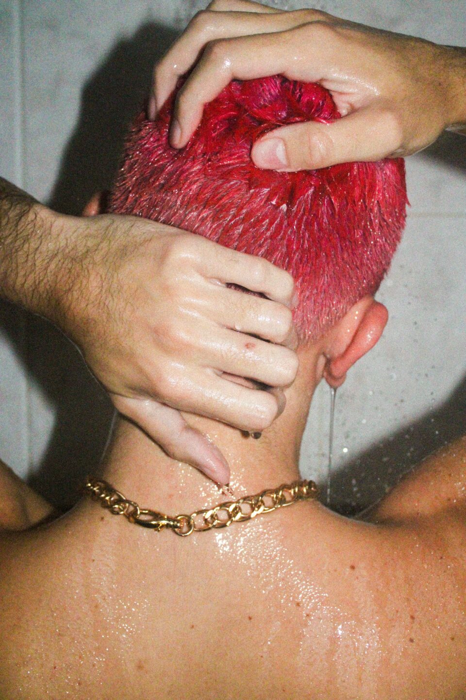 Mann mit pinken Haaren beim Haarewaschen