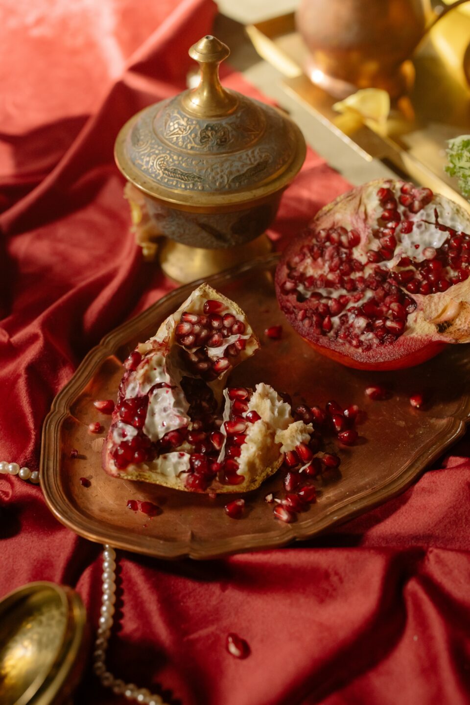 Granatapfel auf einem roten Tuch mit antiker Dekoration Granatapfel auf einem roten Tuch mit antiker Dekoration