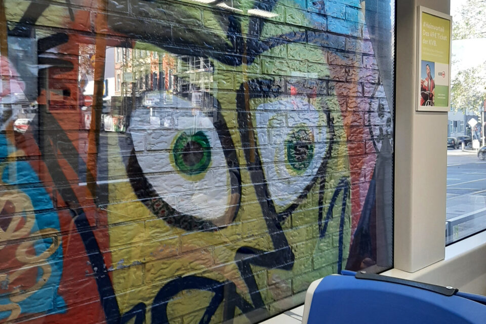 Graffiti, durch das Fenster eines Busses oder einer Straßenbahn aus gesehen.