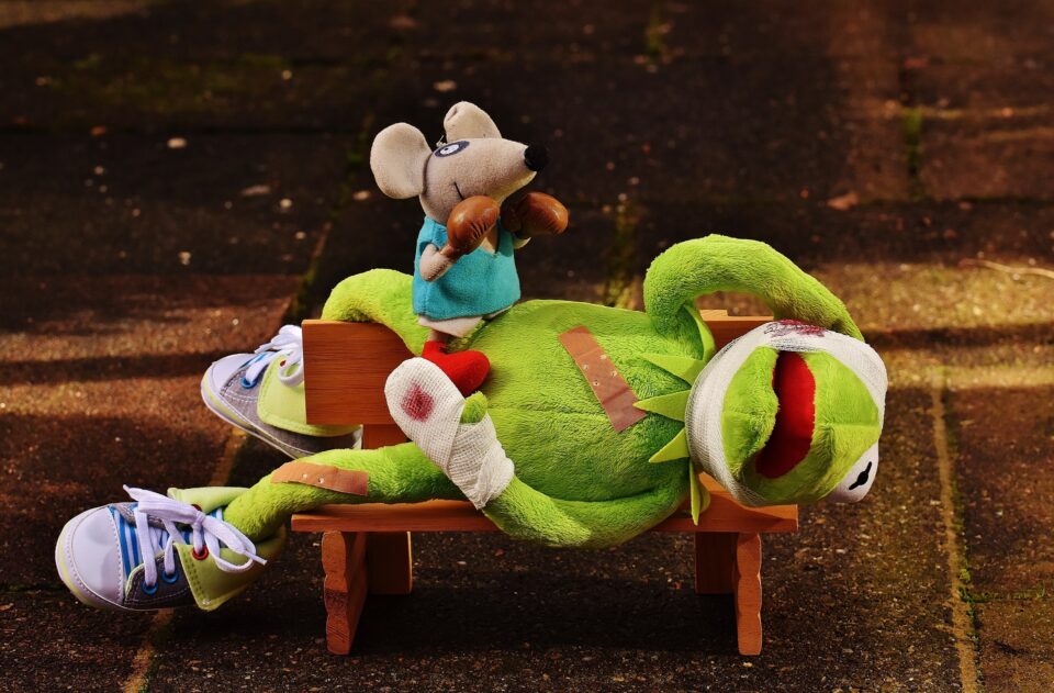Kermit der Frosch kämpft gegen eine Maus mit Boxhandschuhen, er ist verletzt und liegt mit Verbänden auf einem Tisch