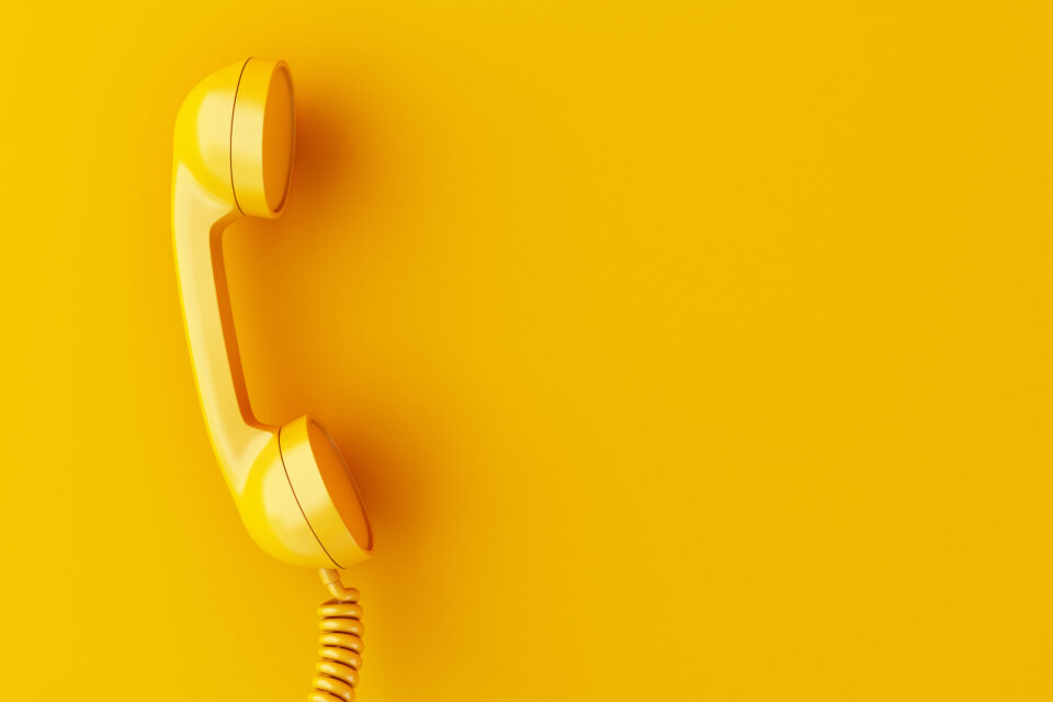 Schreib dir wichtige Nummern auf Sticky Notes und klebe sie überall hin! In Paniksituationen weißt du so, wo du Hilfe holen kannst. (Foto: Adobe Stock) D Phone Reciever On Yellow Background
