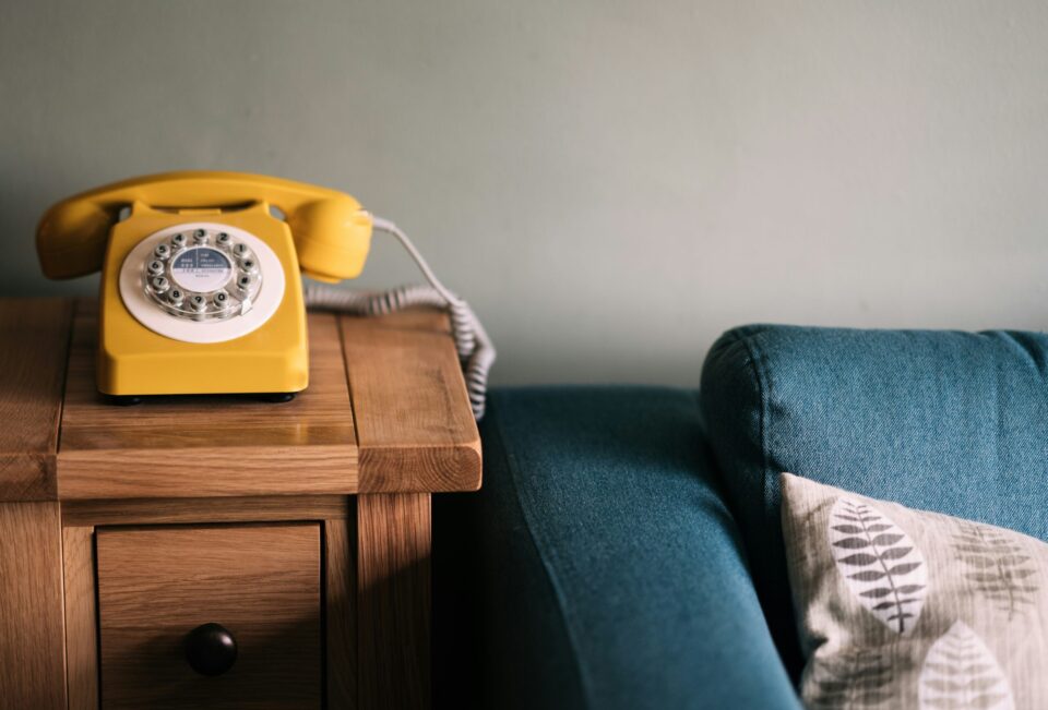 Ein kurzer Griff zum Telefon kann Wunder wirken – soziale Kontakte halten uns zusammen, auch aus der Ferne. (Unsplash/Annie Spratt) gelbes Telefon neben blauem Sofa
