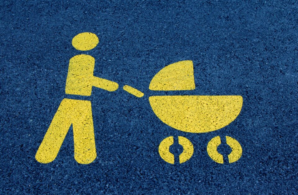 Grafik Person mit Kinderwagen gelb auf blauem Untergrund