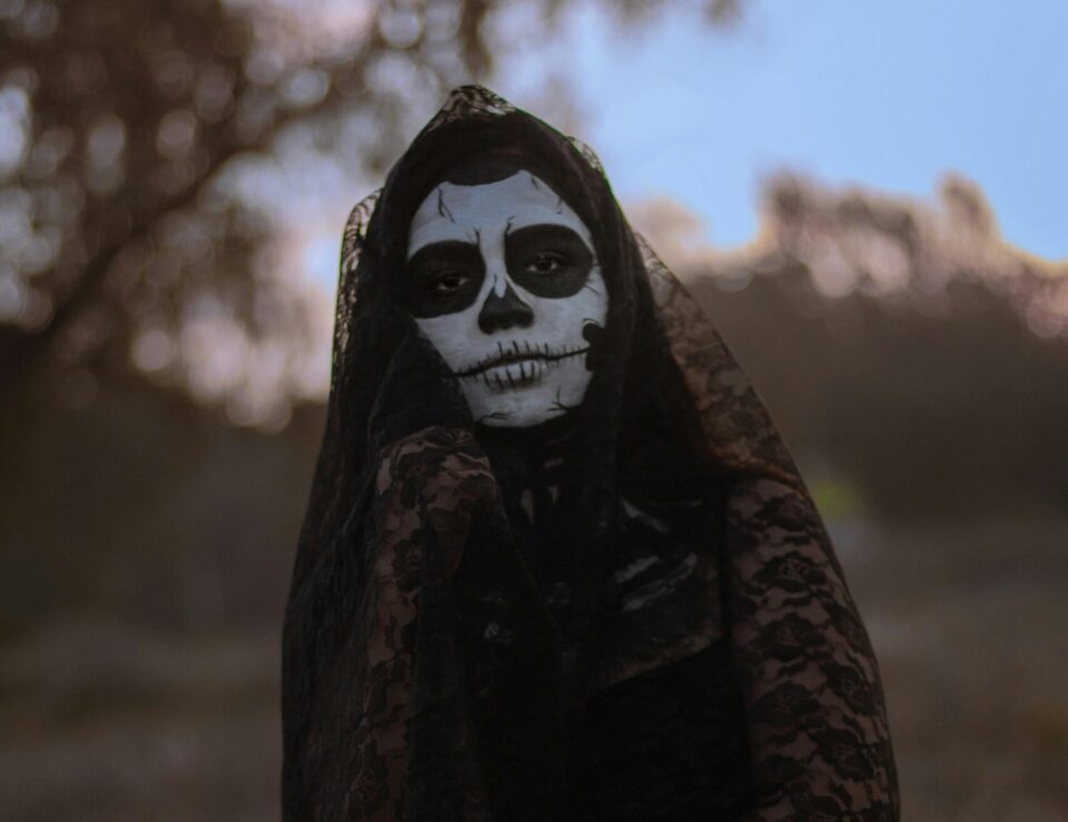 Person mit schwarzer Kleidung und aufgemalter Totenmaske