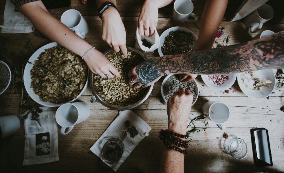 Hände verschiedener Personen bedienen sich an Kräutermischungen